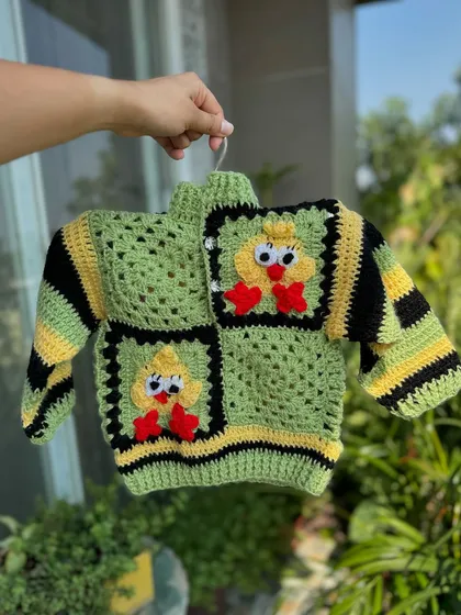 A cozy and cute duck-themed sweater. This piece uses the classic granny square technique to create the duck design, making it a warm and playful top for toddlers.