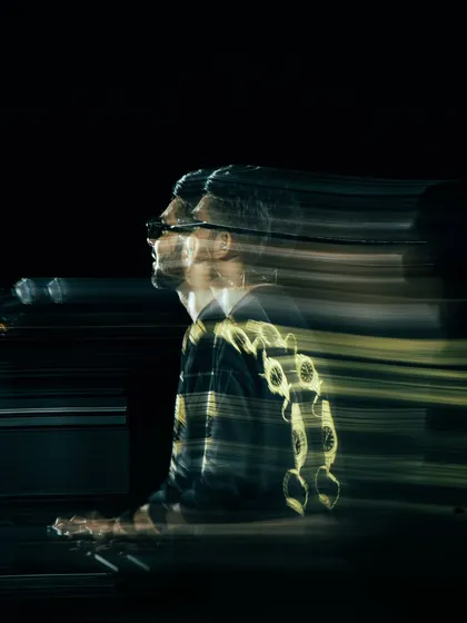 An artistic slow-shutter shot of Anirudh Ravichander at his keyboard, creating a sense of speed and motion that visualizes the energy of his music.