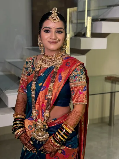 A beautiful portrait of a bride in a blue and orange Paithani saree.