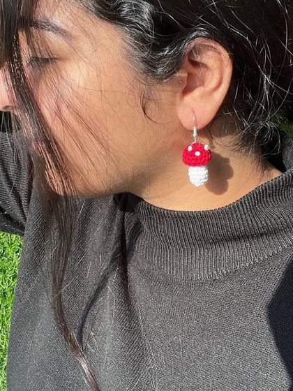 A model wearing the mushroom earrings with a simple black turtleneck. The pop of red and white really stands out.