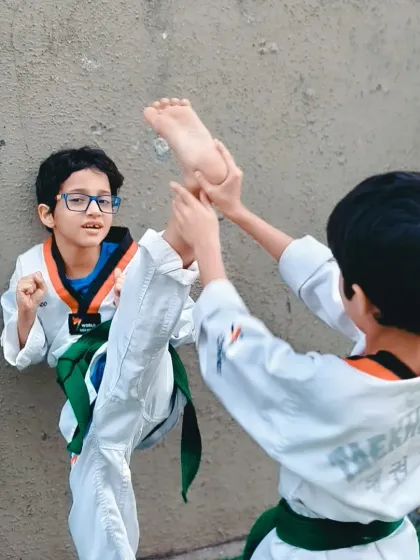 Two boys work together on their wall splits. This kind of partner drill fosters a supportive environment where students motivate each other to improve.