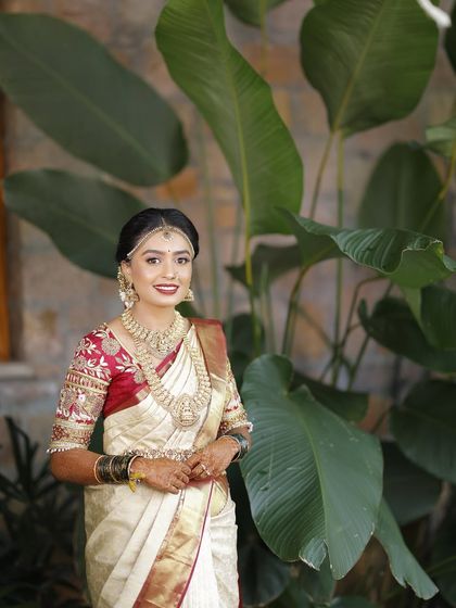 This bride's Muhurtham look is a classic example of my work. The off-white and red Kanjeevaram is paired with flawless HD makeup and traditional gold jewelry.