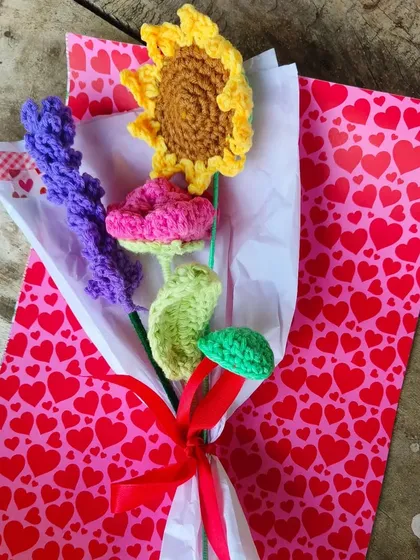 A vibrant and cheerful bouquet featuring a sunflower, a pink rose, and a stalk of purple lavender, all handmade and ready to brighten someone's day.