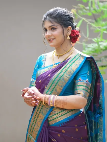 A beautiful portrait of Rujuta in her purple and blue silk saree, with a soft, elegant updo adorned with red roses.