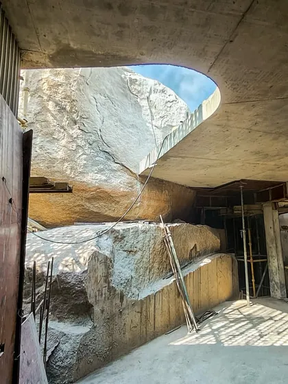 The central boulder of the Lurra House, seen from the basement level. A large cutout in the slab above reveals the stone, creating a powerful connection between the different levels of the home.