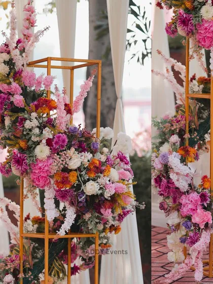 A modern floral installation featuring a cascade of colorful flowers on a golden geometric stand, adding an artistic touch to the decor.
