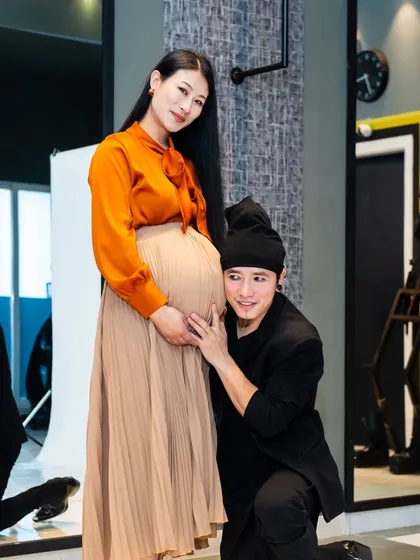 A sweet and classic pose. The dad-to-be kneels to listen to the baby bump, sharing a special moment with his partner and their unborn child.