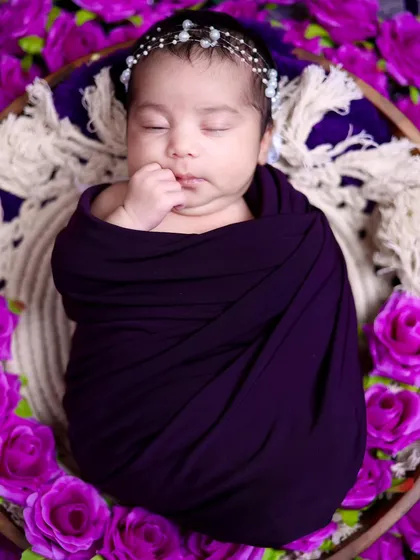 A close-up of the newborn's face, showing the delicate pearl headband and her peaceful sleep.