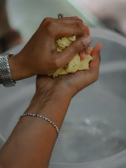 The process of natural dyeing is very hands-on. Here, a participant is squeezing excess water from the fabric before it goes into the dye bath, an important step to ensure even color absorption.