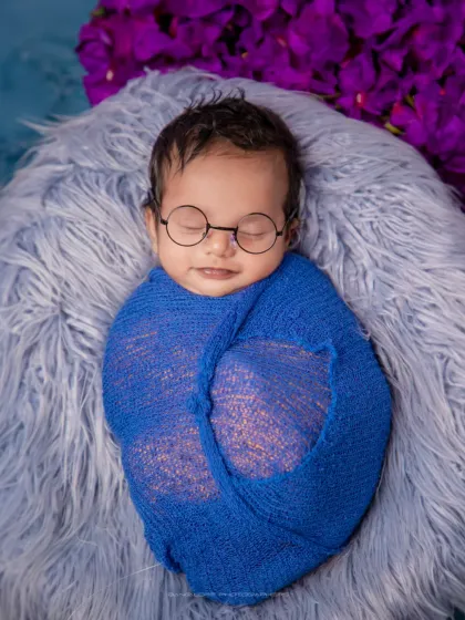 A smile in his sleep. This little one, dressed in a smart blue wrap and tiny glasses, looks ready to dream up big ideas.