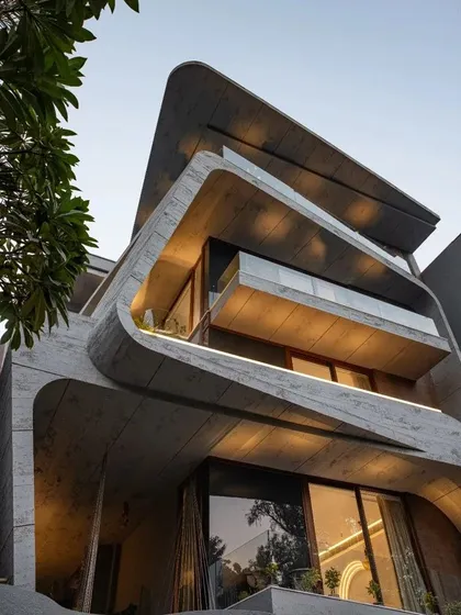 My work is a play between strong geometric forms and organic, curvilinear volumes. This facade demonstrates that balance, using exposed concrete to create a dynamic and visually engaging structure where sharp angles meet soft curves, punctuated by open balconies that connect the inside to the world.