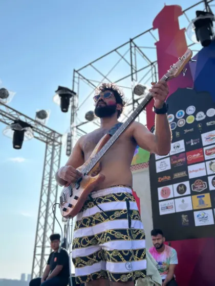 Our bassist rocking out shirtless on a beachside stage in Pattaya. The heat, the sun, and the music created an unforgettable Holi party atmosphere.