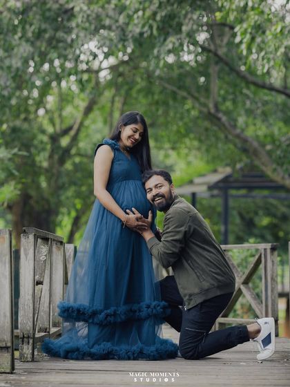 A full-length portrait of the couple on a wooden bridge. The dad-to-be kneels, creating a beautiful composition that celebrates the baby bump.