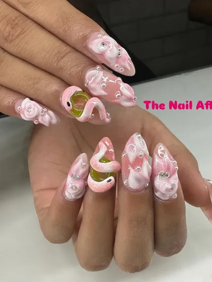 An example of our advanced sculptural work, these stiletto nails feature intricate 3D art, including a pink snake, textured bubbles, and rhinestone details for a dramatic and unique style.