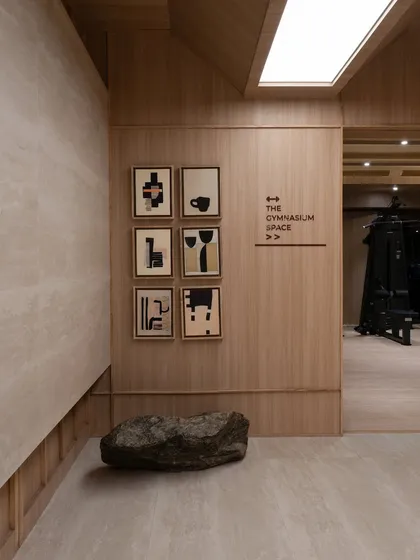 The entrance to the gymnasium, where a collection of abstract art and a natural rock add a touch of curated, organic beauty to the minimalist space.