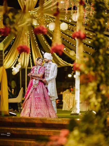 A beautifully framed shot of the couple under a canopy of fairy lights. I use the foreground elements to create depth and draw the viewer's eye to the romantic moment.