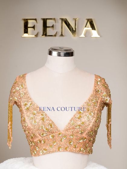 This peach-toned blouse is all about the sparkle and movement. It's crafted from net and covered in sequin and zardozi floral motifs, with dramatic, dangling beaded tassels on the sleeves for a show-stopping effect.