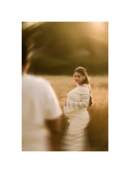 An artistic and dreamy portrait using a freelensing technique to create a soft, swirling blur. The focus remains on the mother-to-be, making her the magical center of this golden-hour shot.