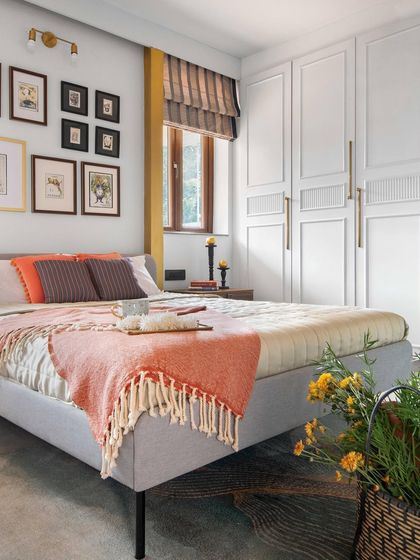 We used a variety of textures and warm colors in this bedroom to create a cozy and inviting atmosphere. A gallery wall of botanical prints adds a personal touch, while the paneled wardrobe provides ample storage with a classic aesthetic.
