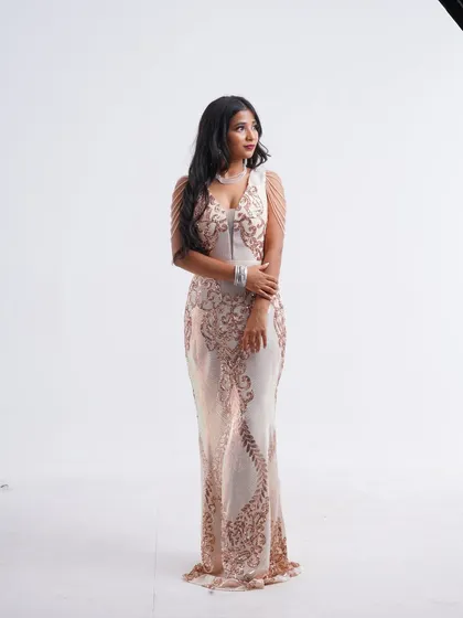 A beautiful full-length shot of a light gold sequin gown with delicate shoulder chain details. This dress offers a soft, ethereal glamour.