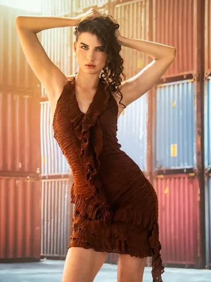 An industrial setting with shipping containers, created with projection. The warm lens flare adds a cinematic touch, contrasting the hard, industrial lines with the soft, flowing dress.
