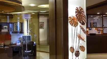 A detail from the Egon Zehnder office, where a backlit panel with copper monstera leaf cutouts acts as a decorative light feature, bringing an element of nature indoors.