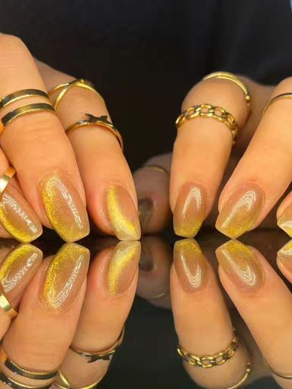 A full set of the glowing golden-yellow cat-eye nails, styled with gold rings.