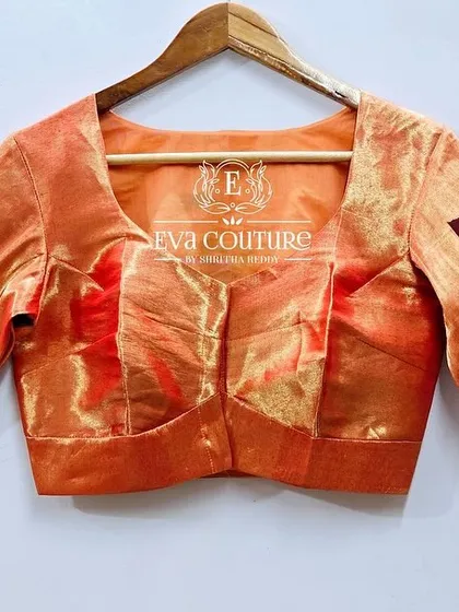 The front view of the peach-colored Paithani silk blouse. The simple front allows the intricate work on the sleeves and back to stand out.
