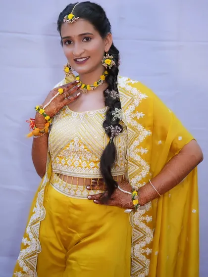 A full-length portrait of the bride in her Haldi outfit, a stylish yellow co-ord set with beautiful embroidery.