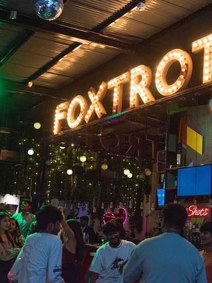 The iconic 'Foxtrot' sign glowing above a lively dance floor. It's a popular spot and I love bringing my energy there.