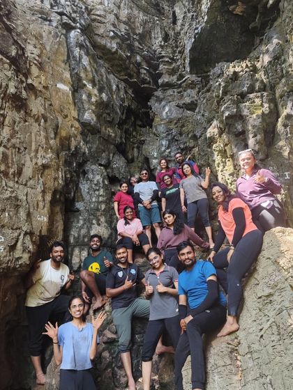 A large group posing for a photo on the rocky terrain inside a cave.