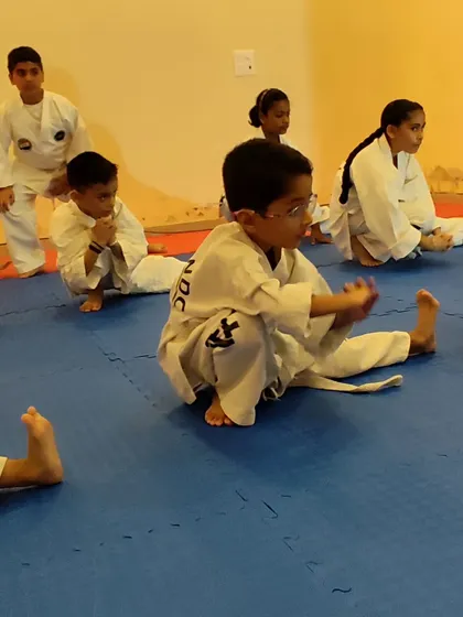 Young students work on their stretching and flexibility, an essential part of preventing injuries and mastering high kicks.
