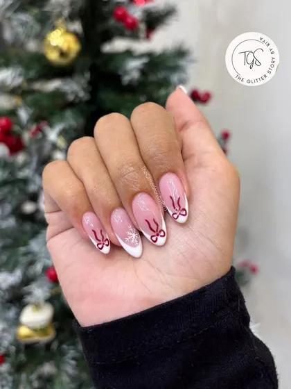 A full view of the Christmas-themed French manicure, showing the almond-shaped nails with cute bow and snowflake details.