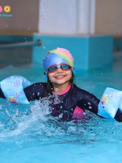 Pure joy in a splash. A young guest having the time of her life at a pool party, fully equipped with arm floaties for safety and fun in our ozonized, gentle-on-the-skin water.