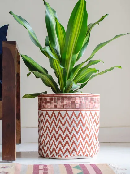 Who says storage has to be plain? Our block-printed fabric basket, featuring a vibrant chevron pattern, is a perfect example of functional art. Use it as a floor planter or to store throws and magazines with a pop of color.