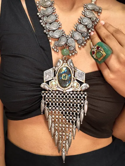 A different perspective on our heritage reimagined. This oxidized necklace features a paisley motif collar and a large pendant with a central stone and silver tassels.
