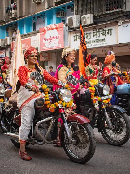 A group of women on motorcycles, dressed in colorful traditional attire, participate in the Gudi Padwa Shobha Yatra in Mumbai.