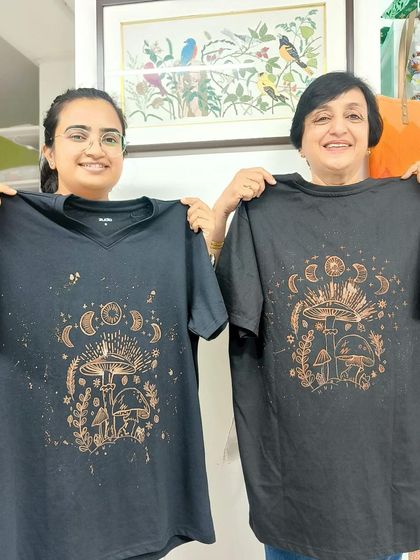 Two participants proudly holding up their matching mushroom-themed bleach art t-shirts.