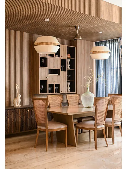 This dining area is wrapped in the warmth of wood, from the fluted wall panels to the cane-woven chairs. We designed this space to feel like a cohesive, modern sanctuary, using different textures of wood to add depth and character.