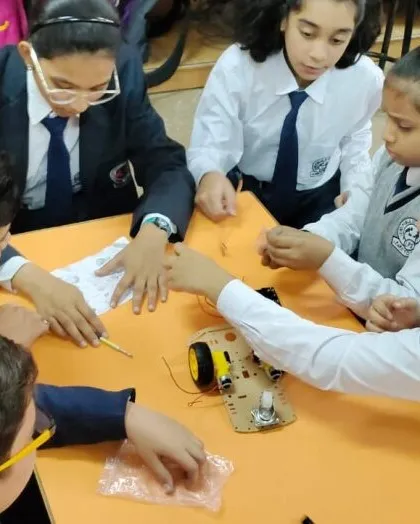 Collaboration is key to innovation. Here, a team of students works together to assemble and wire their robotic car during one of our hands-on school workshops.