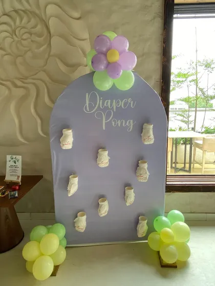 Fun and games at the baby shower with a custom 'Diaper Pong' board. This interactive element is designed to match the party's color scheme and adds a playful touch to the event.