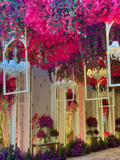 The alchemy of hues is truly unreal. This walkway features a ceiling of magenta leaves and hanging white chandeliers, creating a magical and colorful journey. 🩷💜
