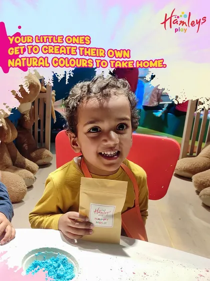 Look at that smile! A young child proudly holds up his finished packet of homemade natural Holi colors. This is what play with purpose looks like.