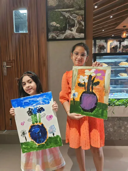 Two young sisters proudly displaying their finished floral vase paintings. It’s so rewarding to see kids explore their creativity and leave with art they are proud of.
