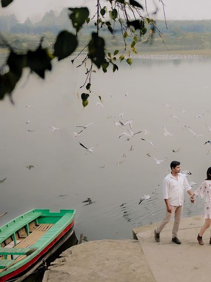 A candid moment of the couple walking hand-in-hand along the riverbank, with their boat waiting nearby. This shot tells the story of their day together.