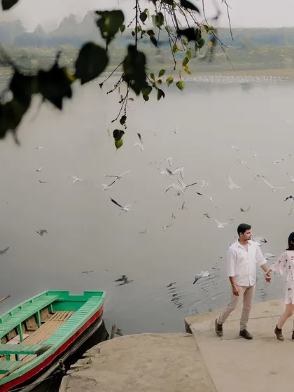 A candid moment of the couple walking hand-in-hand along the riverbank, with their boat waiting nearby. This shot tells the story of their day together.