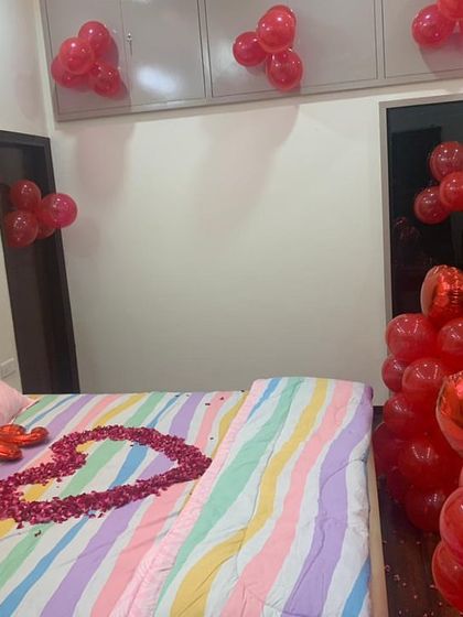 A view of a 'Just Married' room decoration, showing the foil balloons and the bed decorated with a heart made of rose petals and balloon arrangements.