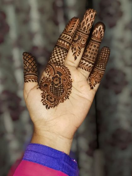 A simple but intricate party henna design, focusing on the palm and fingers.
