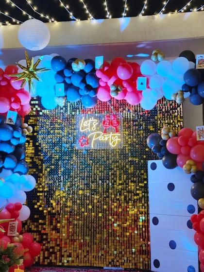 A close-up of the casino-themed Diwali backdrop, featuring a gold sequin wall, a red, black, and white balloon arch, and a "Let's Party" neon sign.