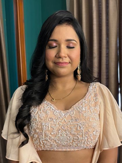 A close-up of the peachy makeup look, showing the delicate shimmer on the eyelids and the flawless, glowing skin.